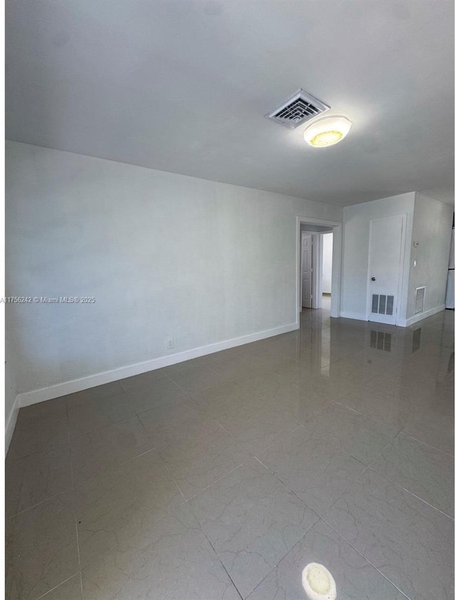 spare room with baseboards and visible vents