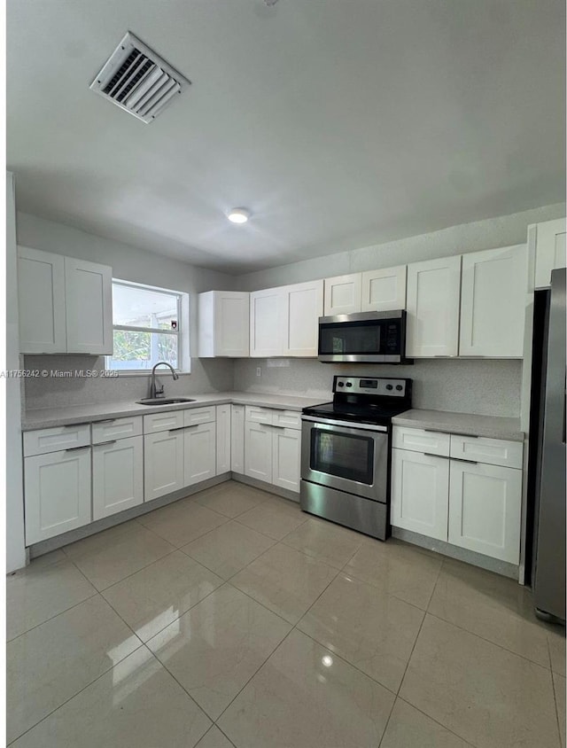 kitchen featuring stainless steel appliances, light countertops, visible vents, white cabinets, and a sink