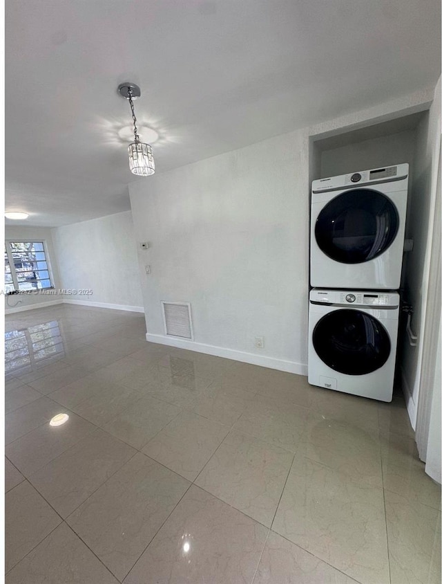 laundry room featuring laundry area, stacked washing maching and dryer, visible vents, and baseboards