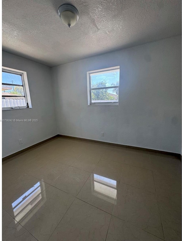 unfurnished room with a textured ceiling and baseboards