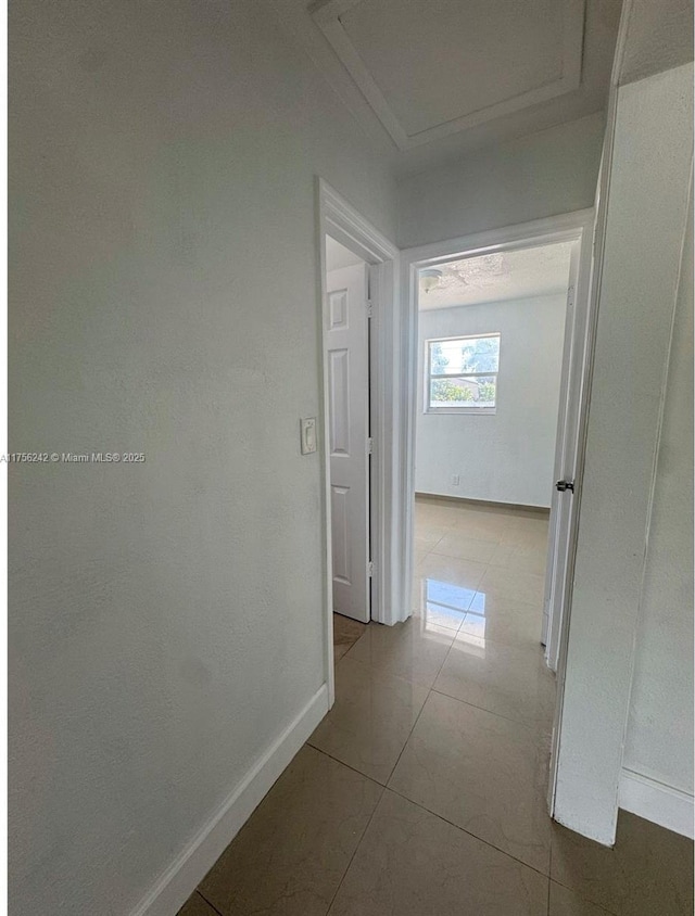 hall featuring tile patterned flooring and baseboards