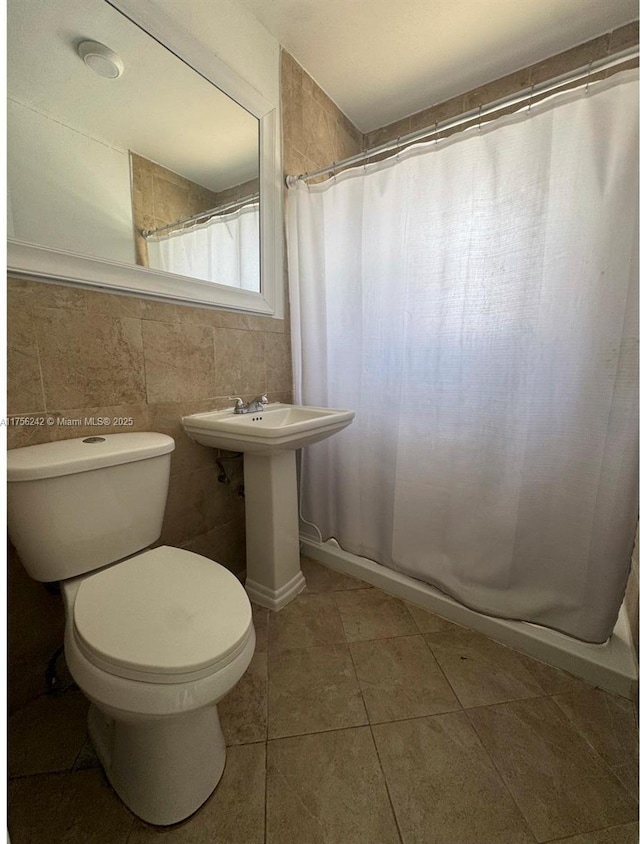 full bathroom with a shower with curtain, tile walls, toilet, and tile patterned floors