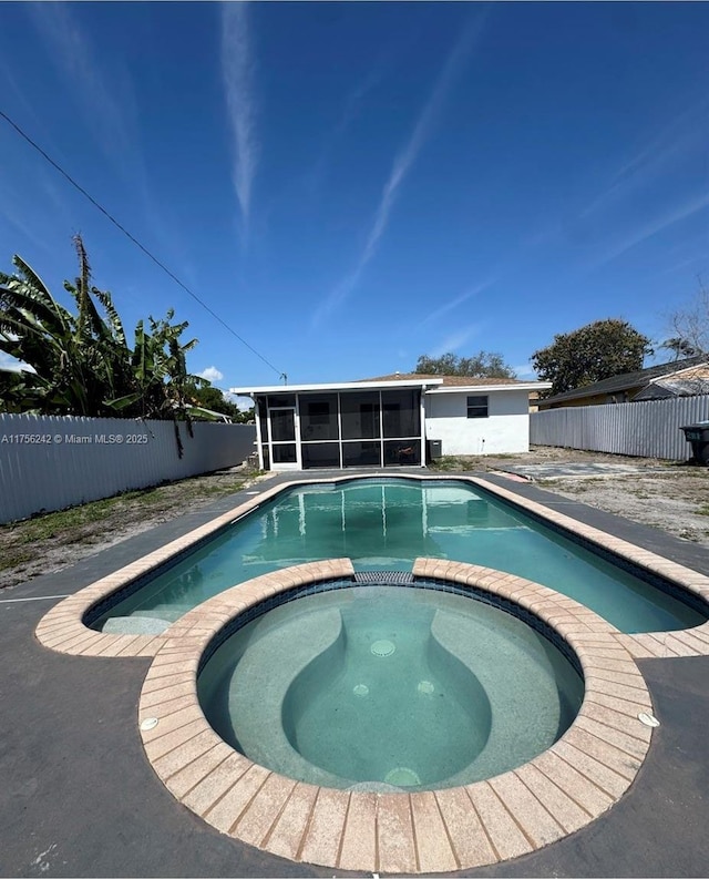 view of pool with a pool with connected hot tub, a fenced backyard, and a sunroom