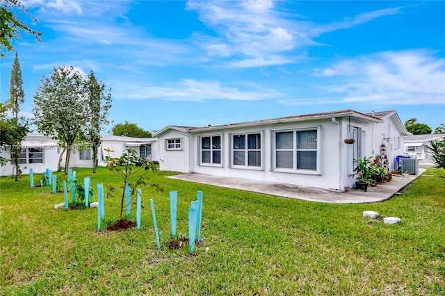 back of property with a yard, central AC unit, and stucco siding