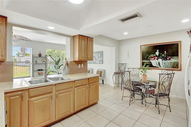 kitchen with light countertops, backsplash, a sink, and visible vents