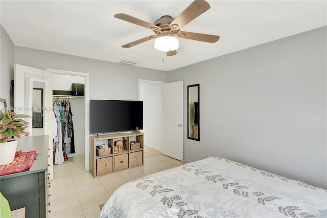 bedroom with a walk in closet, a closet, visible vents, light tile patterned flooring, and ceiling fan