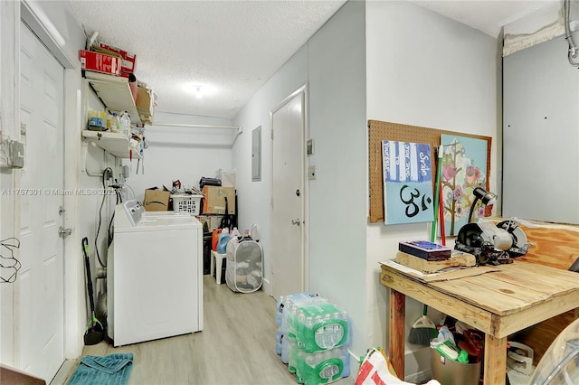 washroom with a textured ceiling, laundry area, separate washer and dryer, light wood-type flooring, and electric panel