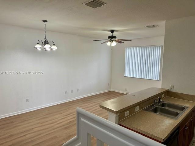 kitchen with pendant lighting, visible vents, a sink, and wood finished floors