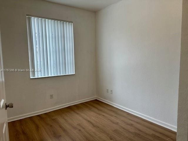 unfurnished room featuring baseboards and wood finished floors