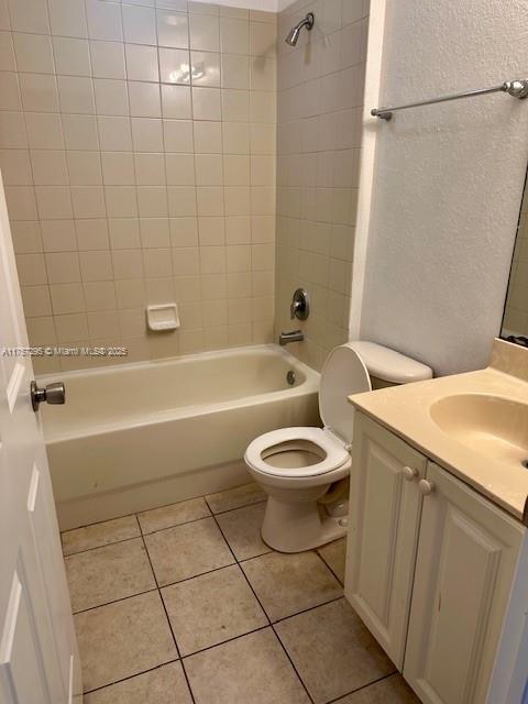 bathroom with a textured wall, toilet, tile patterned floors, tub / shower combination, and vanity