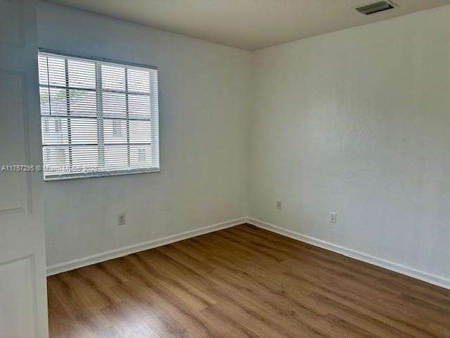 unfurnished room with visible vents, baseboards, and wood finished floors