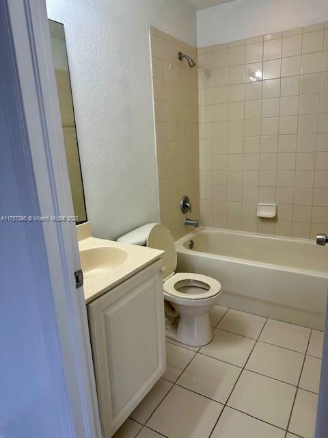 bathroom featuring shower / washtub combination, a textured wall, toilet, vanity, and tile patterned floors