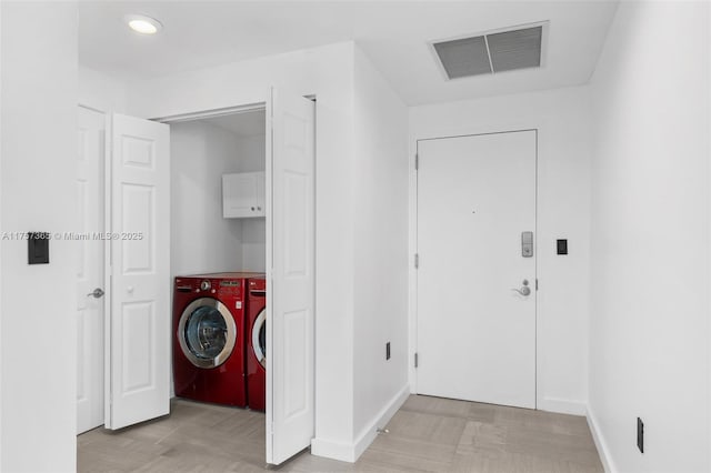 laundry area featuring washing machine and dryer, cabinet space, visible vents, and baseboards