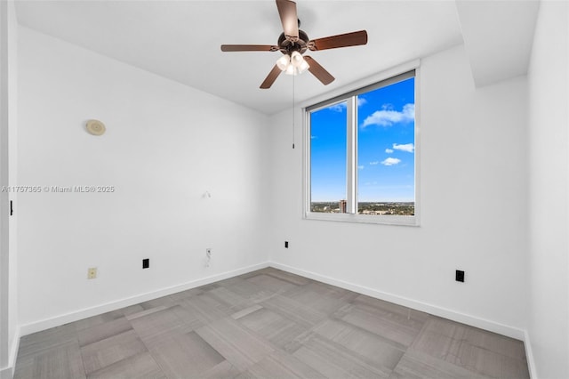 empty room with a ceiling fan and baseboards