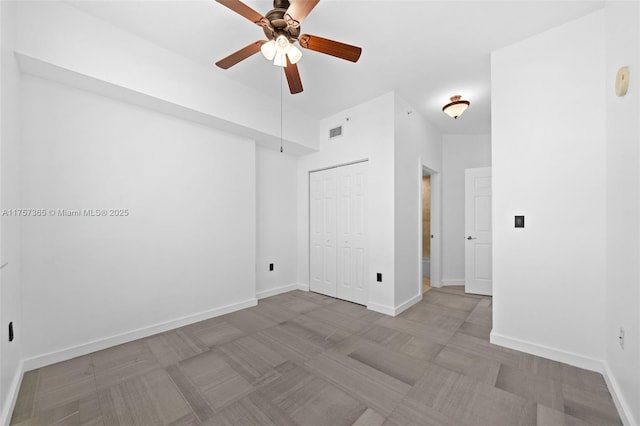 empty room featuring a ceiling fan, visible vents, and baseboards