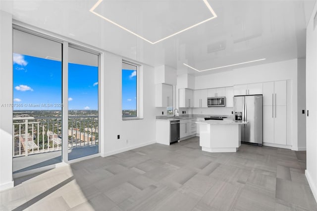 kitchen featuring appliances with stainless steel finishes, a center island, light countertops, white cabinetry, and a sink