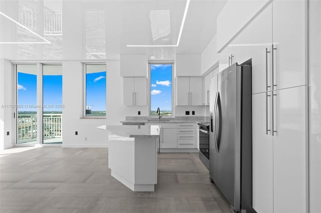 kitchen featuring a sink, white cabinets, appliances with stainless steel finishes, a center island, and modern cabinets