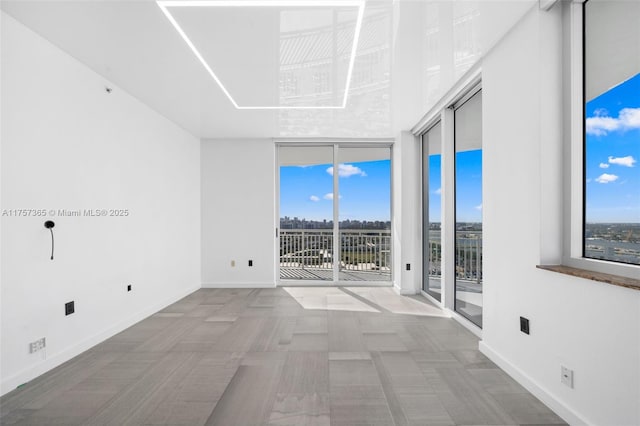 empty room with baseboards and a wall of windows