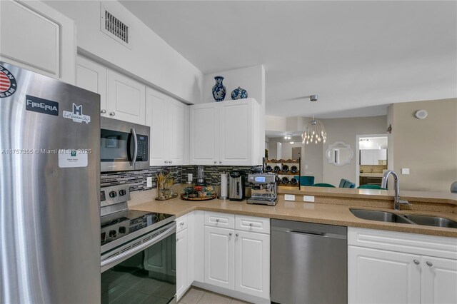 kitchen with light stone counters, stainless steel appliances, tasteful backsplash, visible vents, and a sink