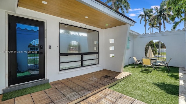 entrance to property featuring a yard and stucco siding