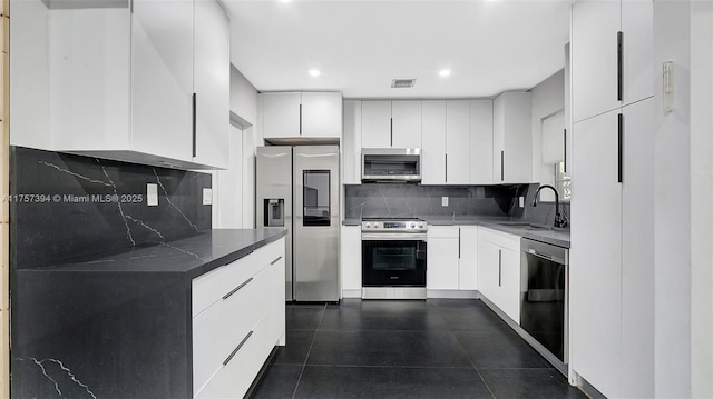 603 N 32nd Ave, Hollywood, FL 33021 - kitchen featuring visible vents, dark countertops, appliances with stainless steel finishes, white cabinetry, and a sink