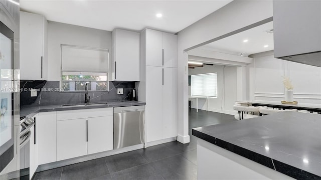 603 N 32nd Ave, Hollywood, FL 33021 - kitchen featuring stainless steel dishwasher, a healthy amount of sunlight, white cabinets, and tasteful backsplash