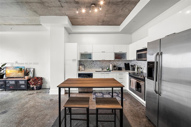 kitchen featuring tasteful backsplash, stainless steel appliances, light countertops, white cabinetry, and a sink