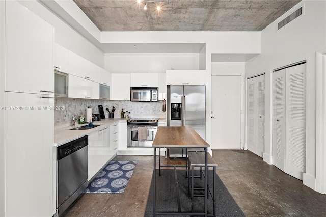 kitchen with stainless steel appliances, visible vents, white cabinetry, a sink, and modern cabinets