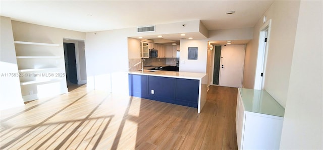 kitchen featuring visible vents, stainless steel microwave, light wood-style floors, a sink, and electric panel