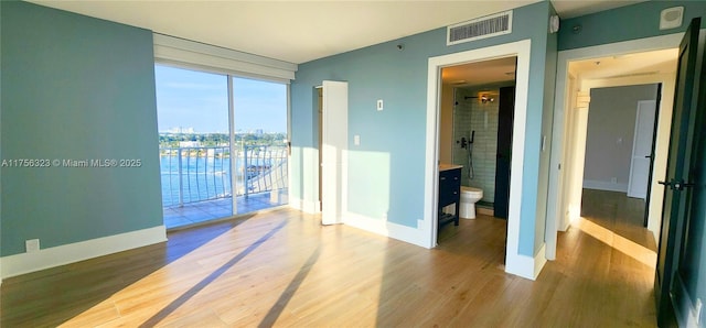 unfurnished room with wood finished floors, visible vents, and baseboards