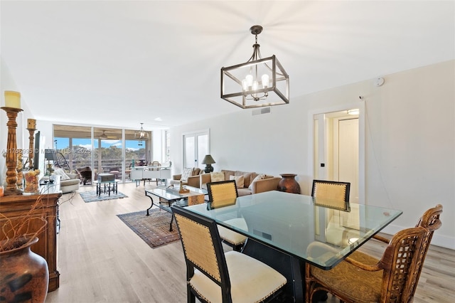 dining room with expansive windows, light wood-type flooring, and a notable chandelier