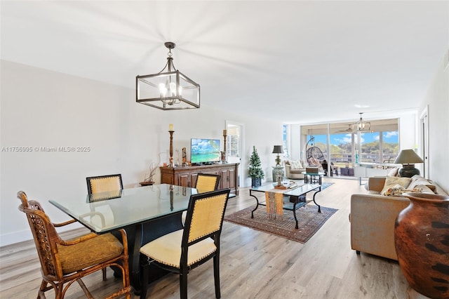 dining space featuring expansive windows, light wood finished floors, baseboards, and a notable chandelier