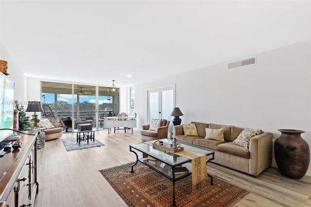 living room featuring light wood-style floors, floor to ceiling windows, and visible vents