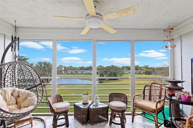 sunroom featuring a ceiling fan and a water view