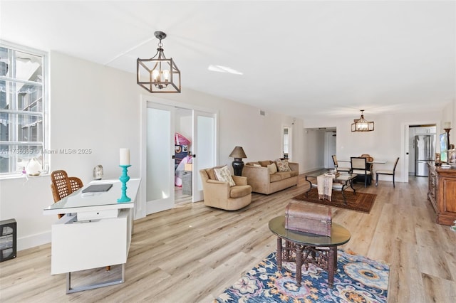 living area with light wood-style flooring, baseboards, and an inviting chandelier