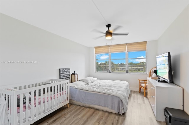 bedroom with a ceiling fan, baseboards, and light wood finished floors