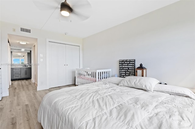 bedroom featuring a closet, visible vents, ceiling fan, and light wood-style flooring