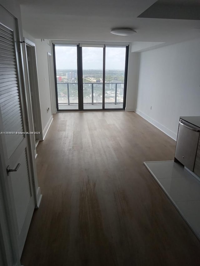 unfurnished living room featuring expansive windows, baseboards, and wood finished floors