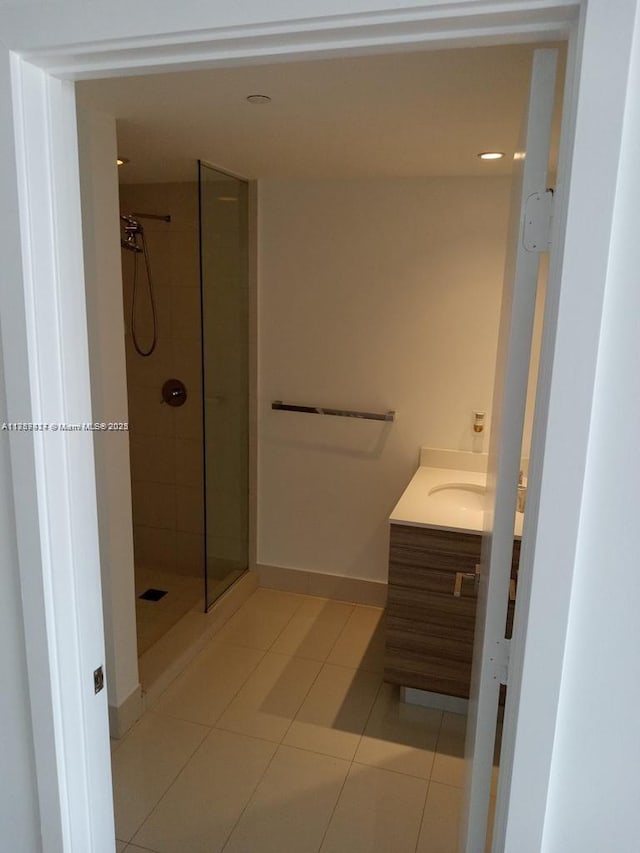 full bath featuring a shower stall, vanity, baseboards, and tile patterned floors