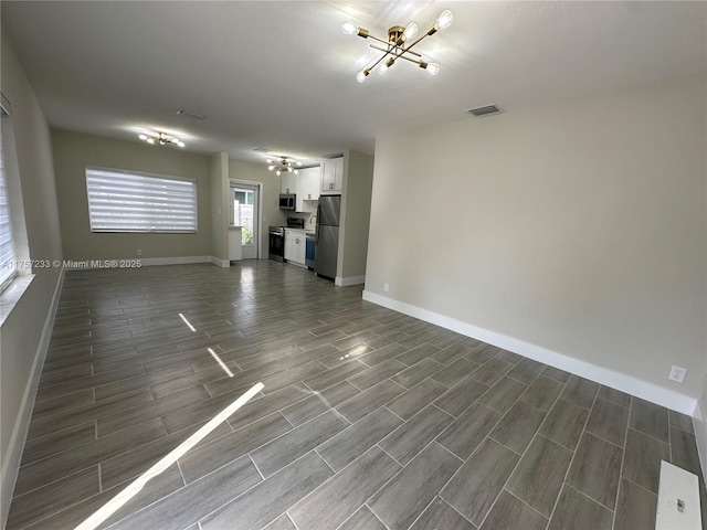 unfurnished living room featuring visible vents, baseboards, and wood finish floors