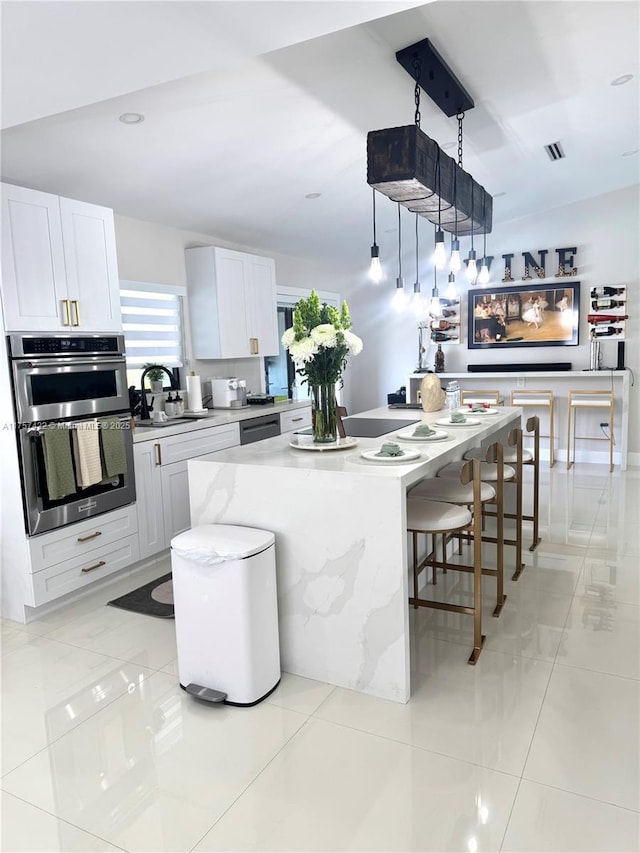 kitchen featuring light tile patterned floors, dishwasher, a center island, stainless steel double oven, and a sink