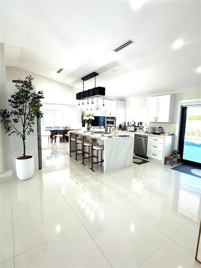 kitchen with stainless steel appliances, a kitchen island, visible vents, white cabinetry, and light countertops