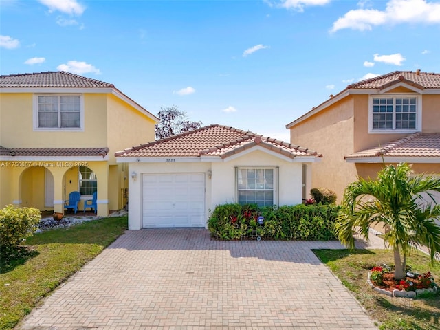 mediterranean / spanish-style home featuring a garage, a tile roof, decorative driveway, and stucco siding