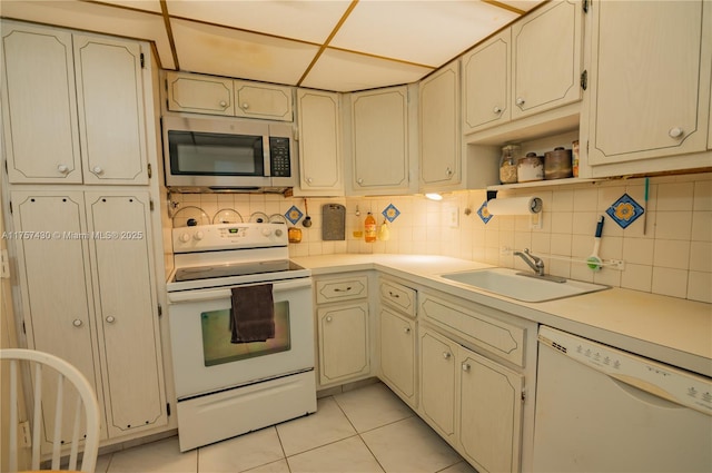 kitchen featuring light tile patterned floors, tasteful backsplash, light countertops, a sink, and white appliances