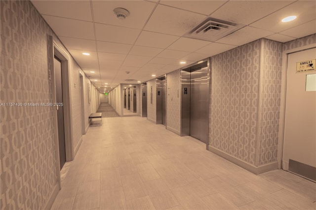 corridor with a paneled ceiling, elevator, visible vents, and recessed lighting