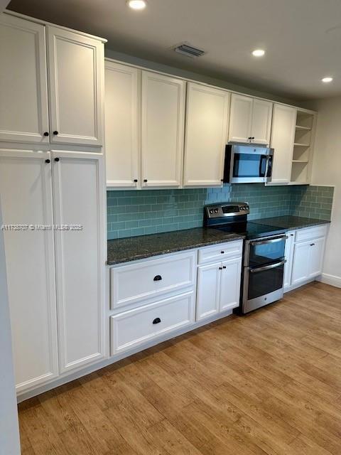 kitchen featuring stainless steel appliances, light wood-style flooring, and white cabinets