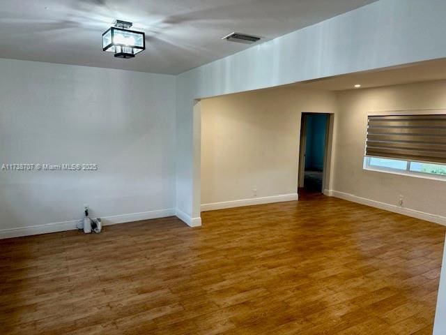 spare room with baseboards, visible vents, and wood finished floors