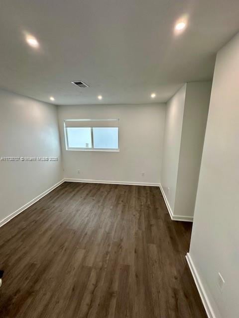 unfurnished room with dark wood-style floors, recessed lighting, visible vents, and baseboards