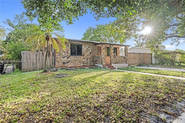 view of front facade with stone siding, a front lawn, and fence