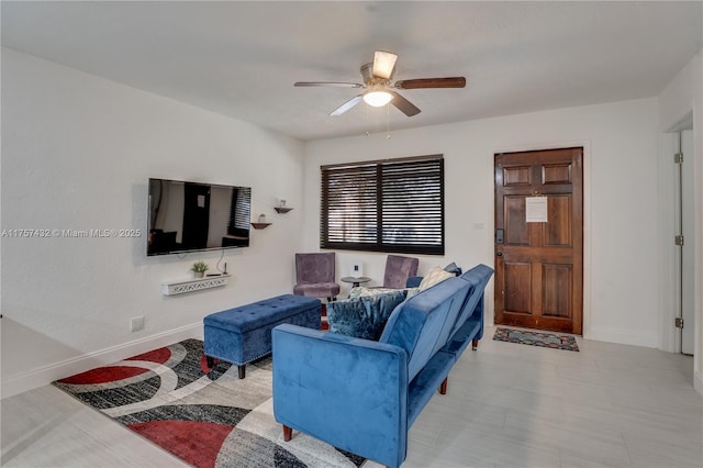 living room with baseboards and a ceiling fan